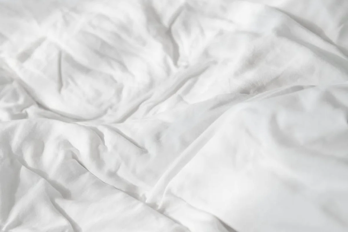 White linen fabric with soft folds and subtle texture.