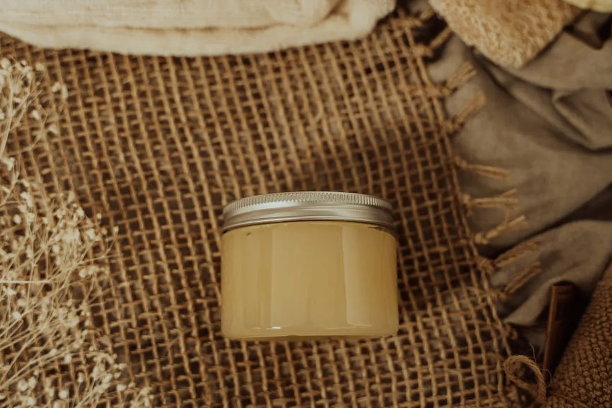 Small beige jar placed on woven burlap with soft fabric folds in the background, conveying natural fibers and fabric care context.