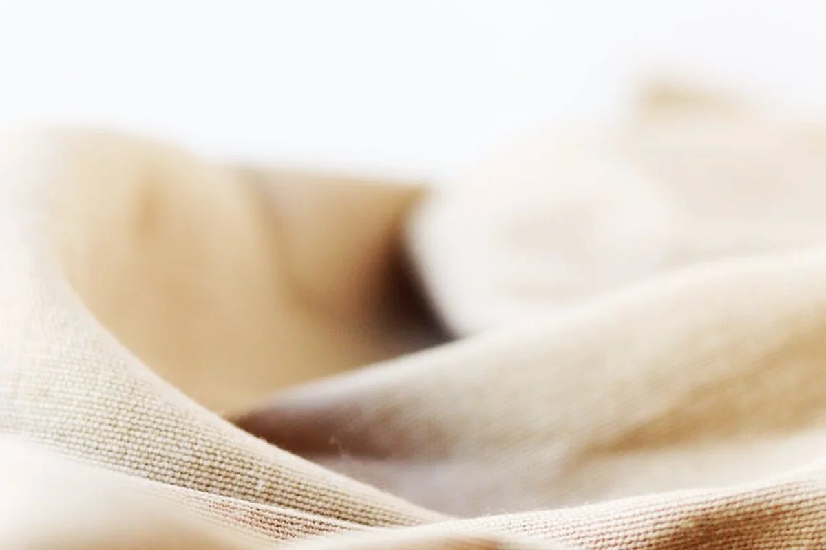 Close-up of beige linen fabric with soft folds and visible weave texture