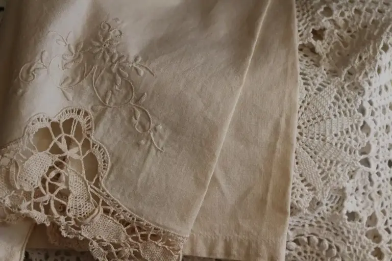 Beige linen fabric with embroidered floral design and crocheted lace trim.