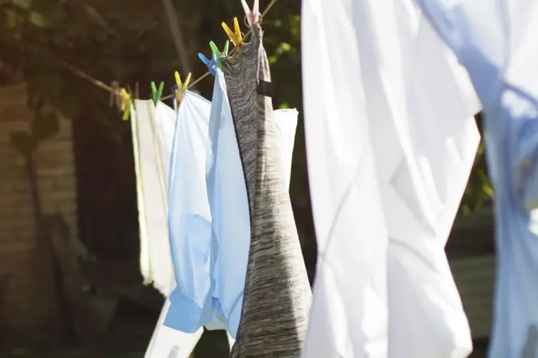 Linen fabrics hanging on a clothesline outdoors to dry, with colorful clothespins