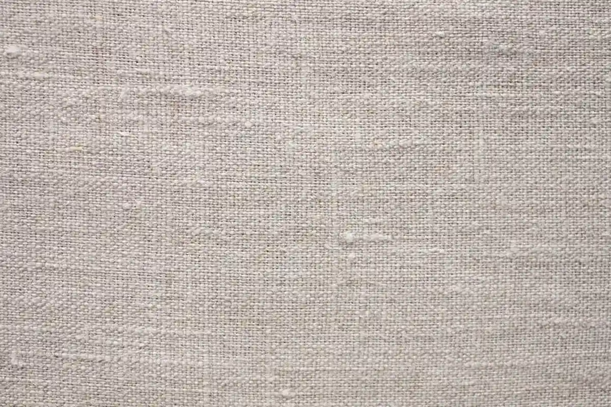 Close-up view of beige linen fabric texture, serving as a neutral background for nylon craft supplies.