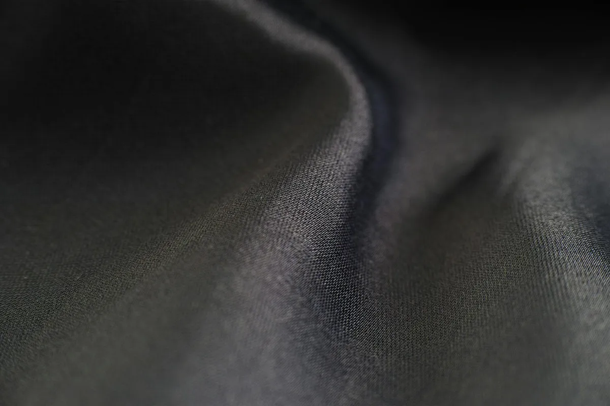 Close-up of dark lyocell fabric texture with smooth, flowing folds