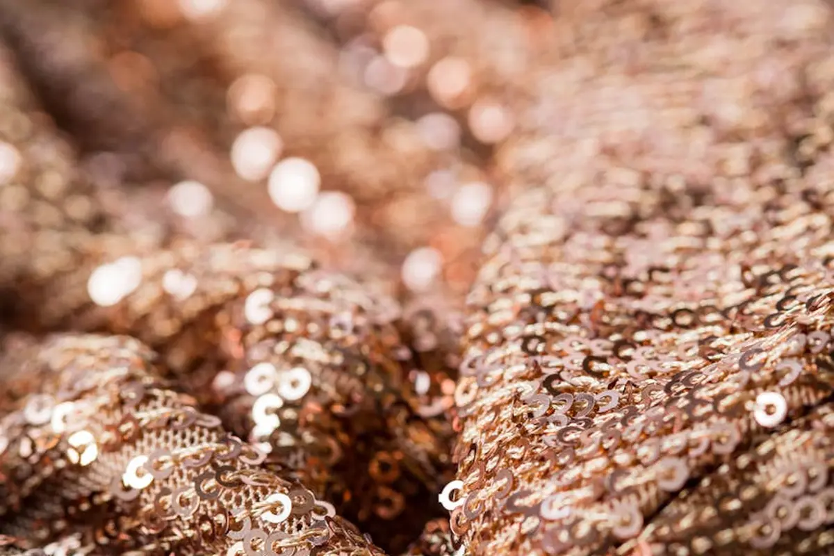 Close-up of bronze-brown sequins on fabric, creating a shimmering textured surface.