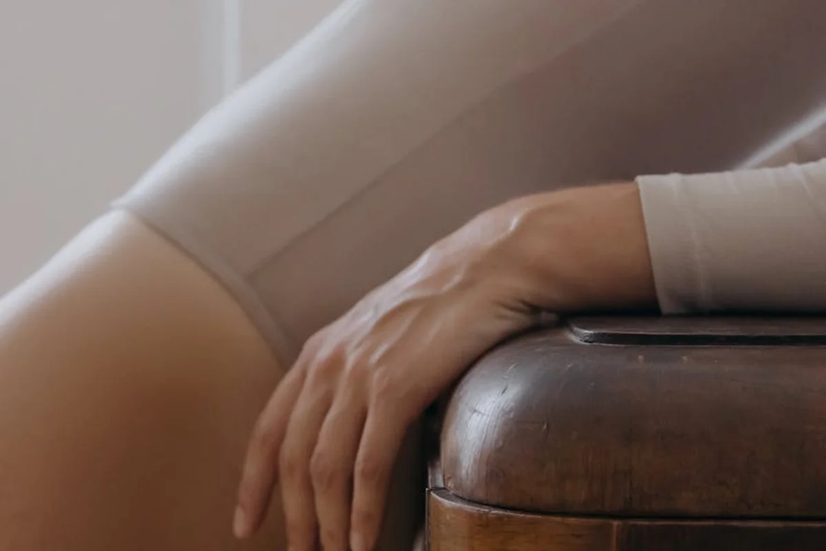 Close-up of a person resting their hand on a wooden surface, with a light-colored sleeve visible, suggesting soft, comfortable fabric.