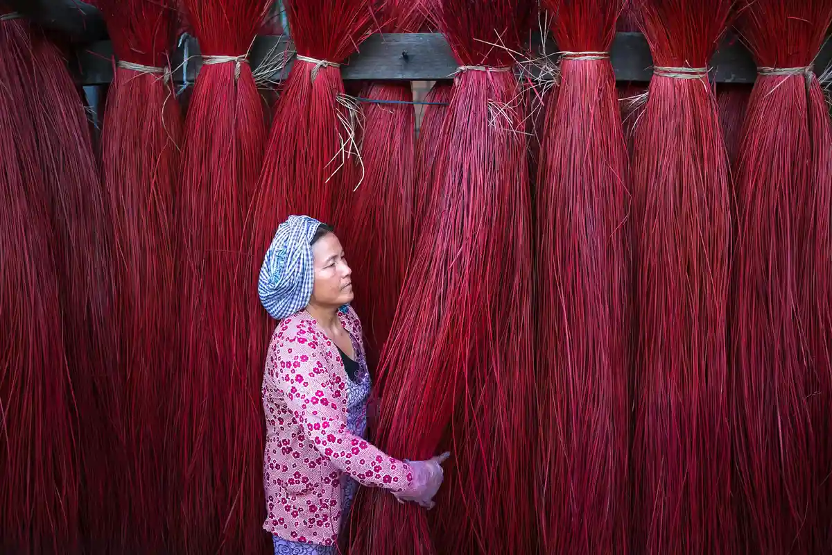 A textile worker standing among tall red lyocell fibers in a dyeing facility