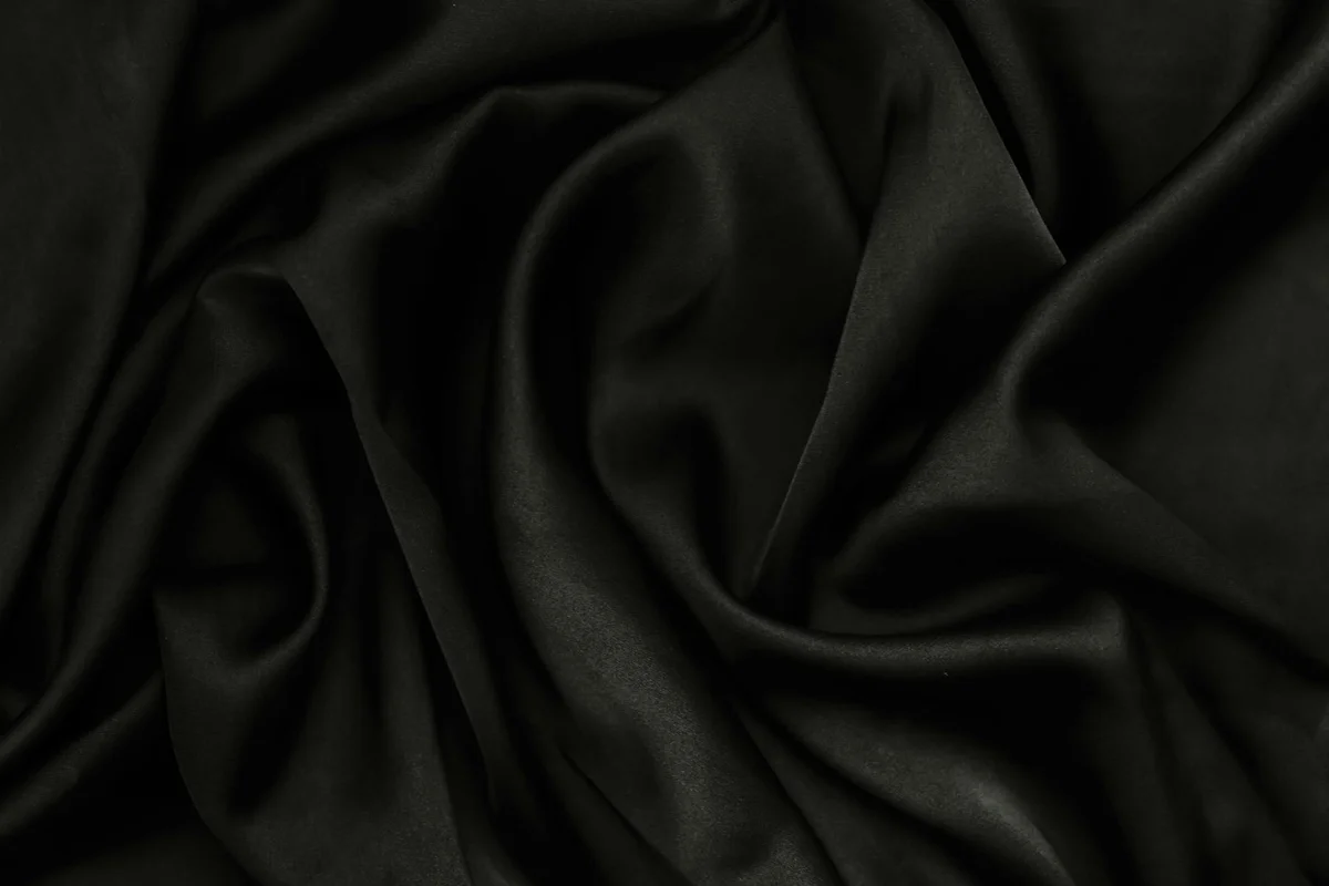 Close-up of dark, smooth fabric with soft folds, illustrating fabric texture and drape