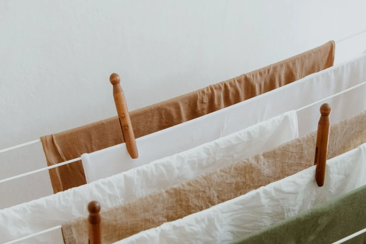 Clothesline with neutral-colored textiles hanging to dry on wooden pegs.