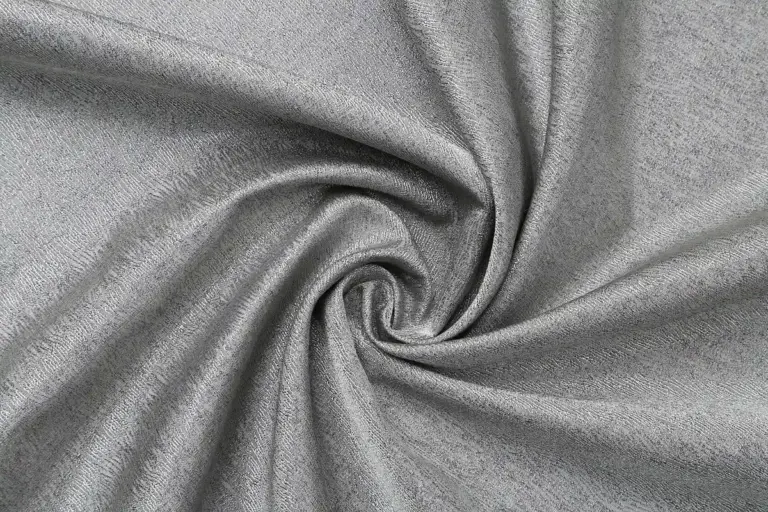 Close-up of soft gray modal fabric twisted into a swirl, showing smooth texture and drape.