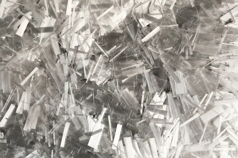 Close-up of numerous shiny, thin rectangular fibers scattered across the frame, resembling shredded plastic or metallic strips.