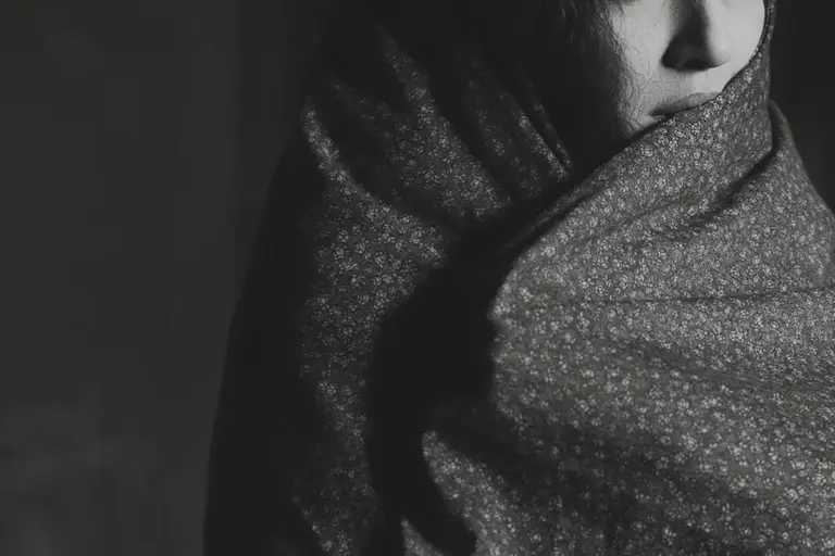Monochrome close-up of a person wrapped in a patterned modal fabric scarf.
