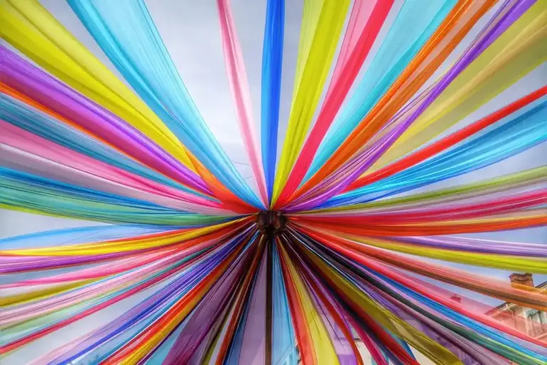 Circular fan of vibrant fabric strips in multiple colors radiating from a central point, illustrating draping and fabric manipulation.