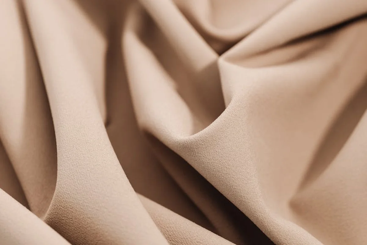 Close-up of beige muslin fabric with flowing folds and soft texture