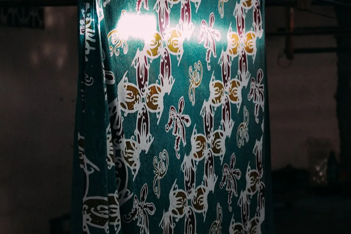 Teal fabric with white floral pattern hanging, illustrating wrinkle-resistant finishes.