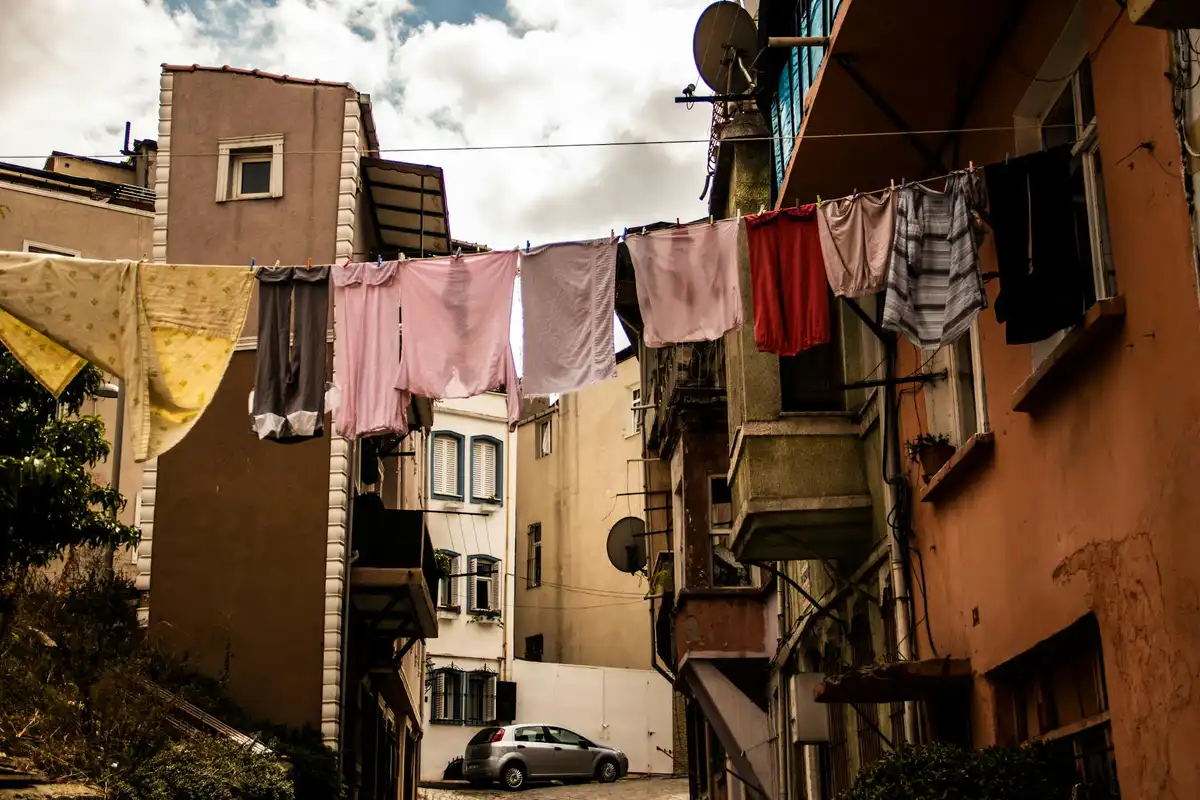 Nylon garments hanging on a clothesline between buildings in a city alley.