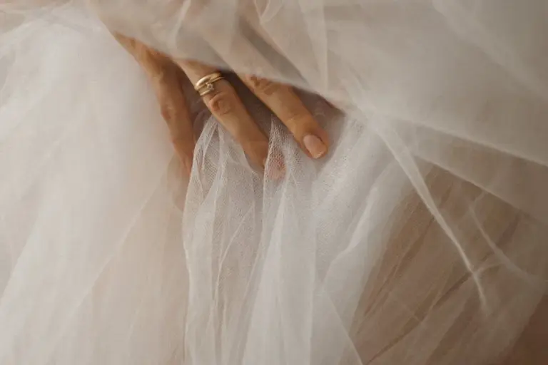 Close-up of hands holding a delicate sheer fabric (veil).