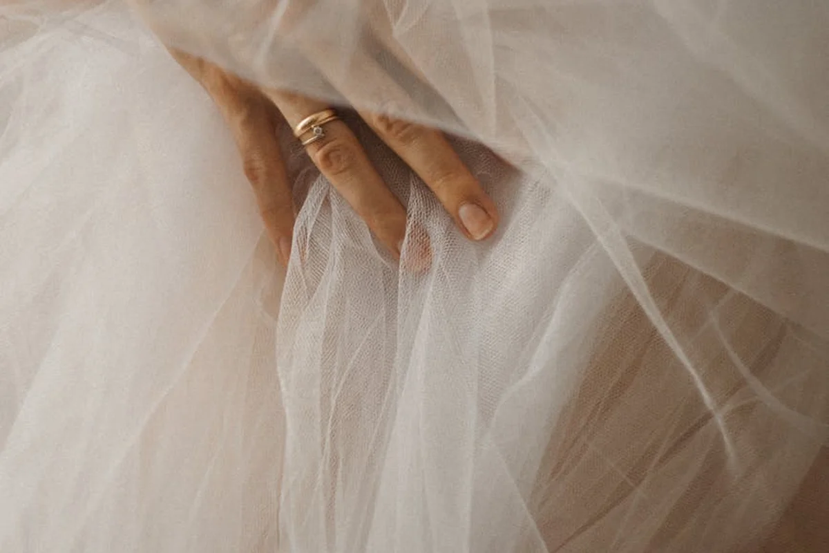 Close-up of a hand touching sheer white nylon fabric, highlighting its delicate texture