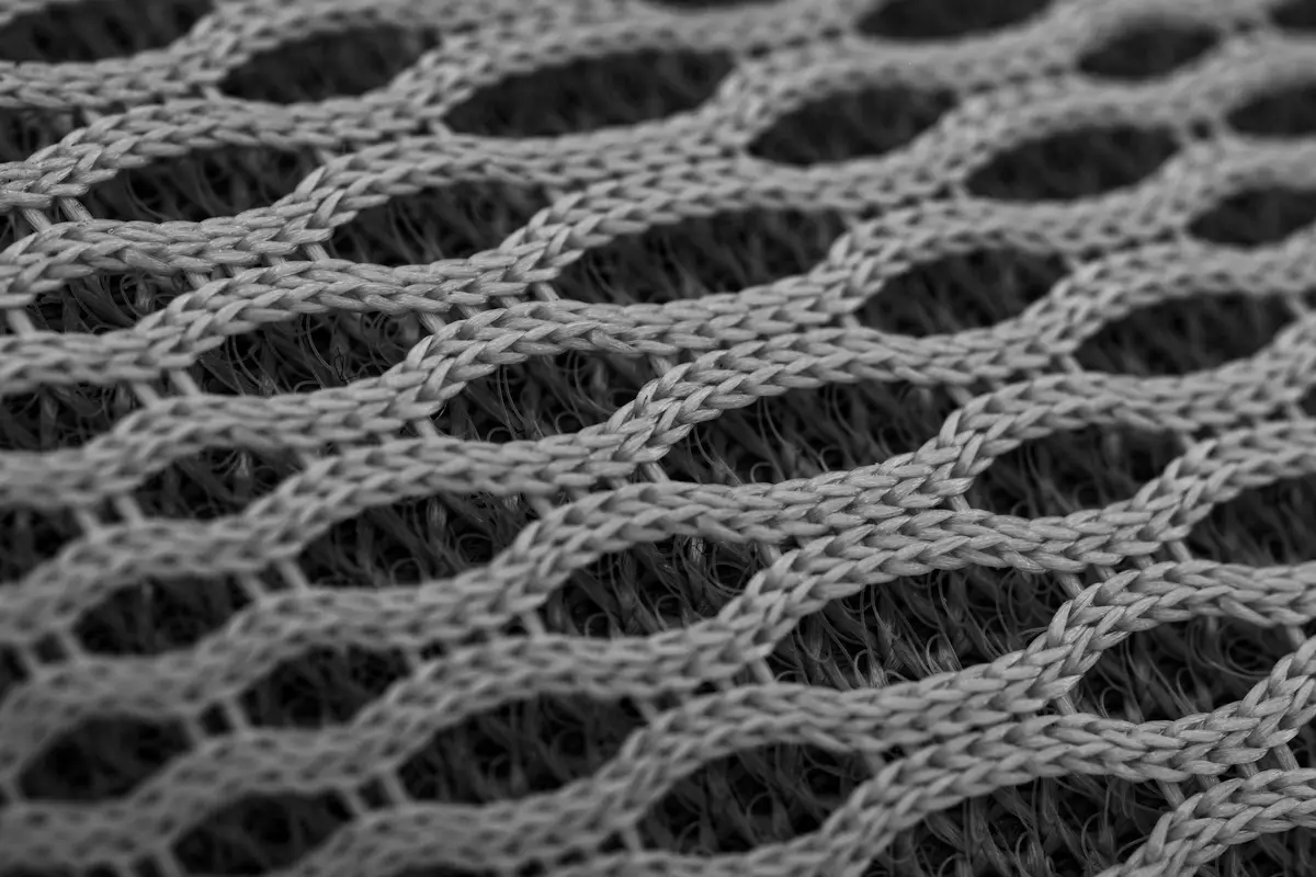 Close-up view of gray nylon mesh fabric showing interwoven fibers and open weave.