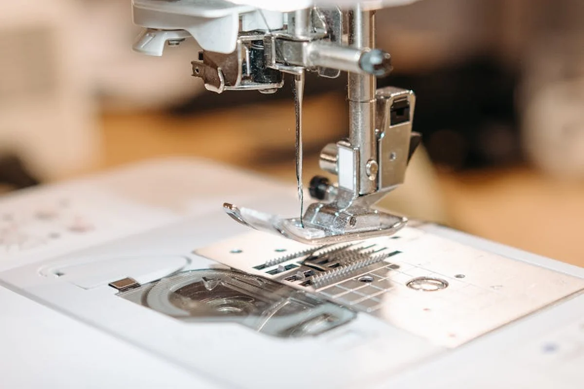 Close-up of a sewing machine needle and presser foot on nylon fabric, about to sew a patch in place.