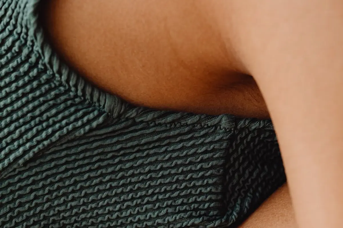 Close-up of a textured nylon-spandex fabric with a ribbed knit pattern and a portion of skin visible nearby to illustrate fabric elasticity.