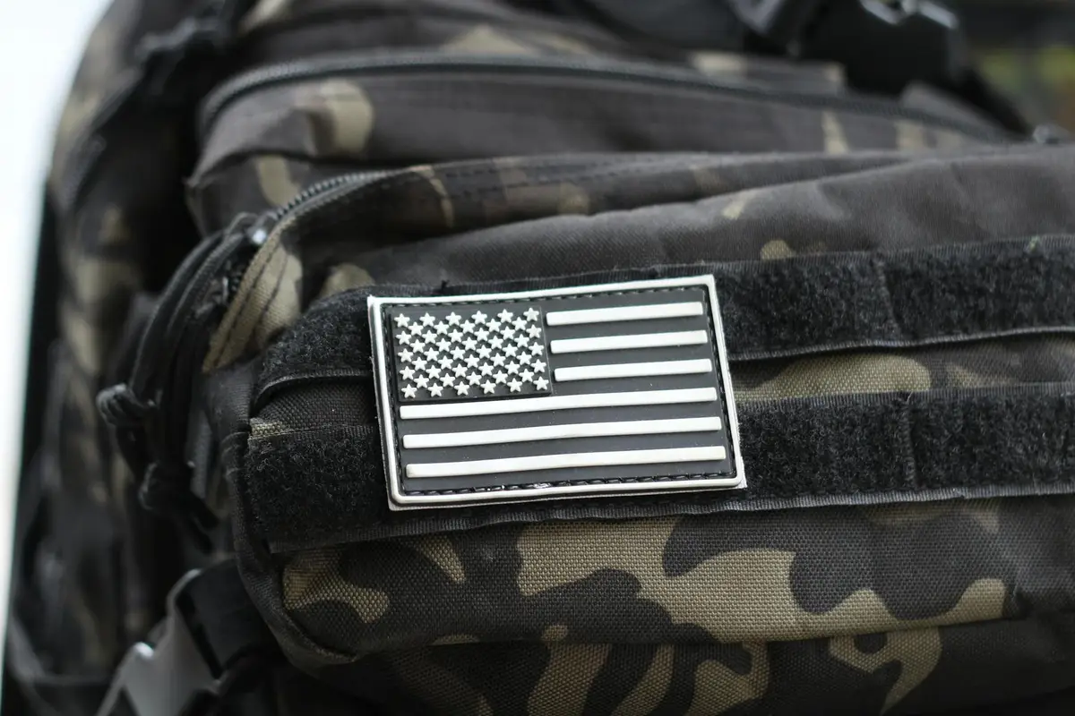 Close-up of a camouflage nylon tactical vest with a monochrome American flag patch.