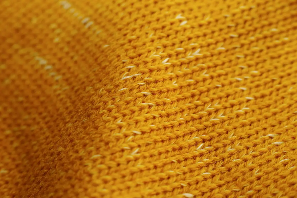 Close-up of orange knitted fabric with white flecks.