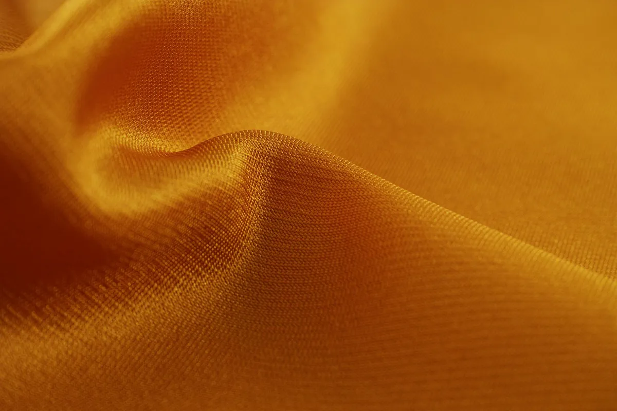 Close-up of vivid orange viscose/rayon fabric with soft folds
