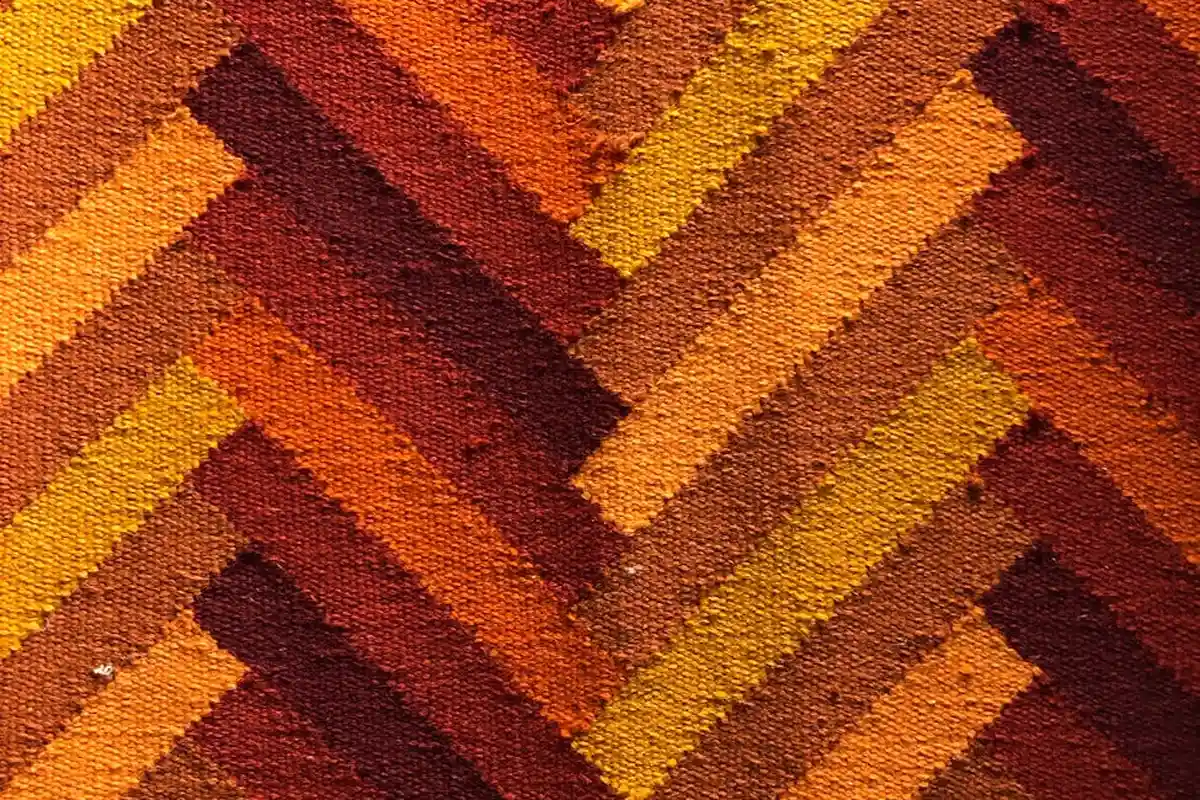 Close-up of a chevron-pattern textile in warm orange, brown, and yellow tones.
