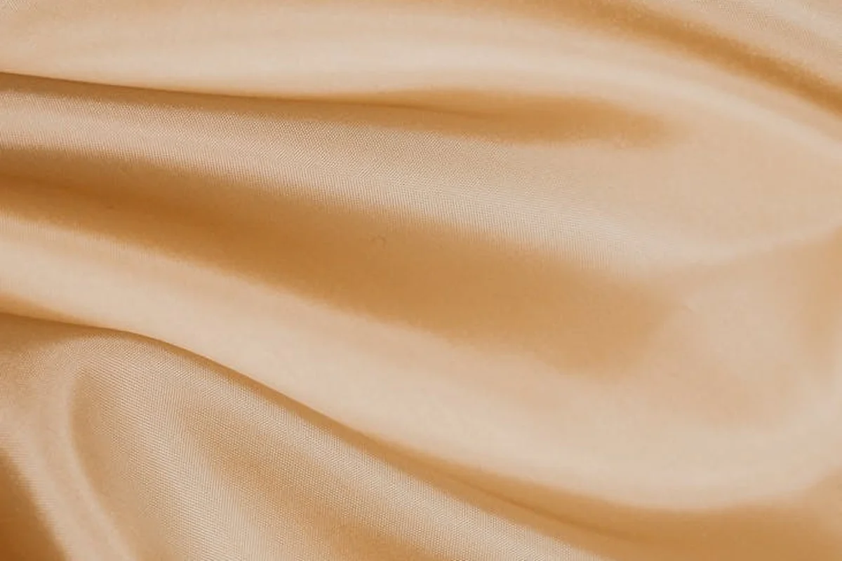 Close-up of peach-colored smooth fabric with soft folds