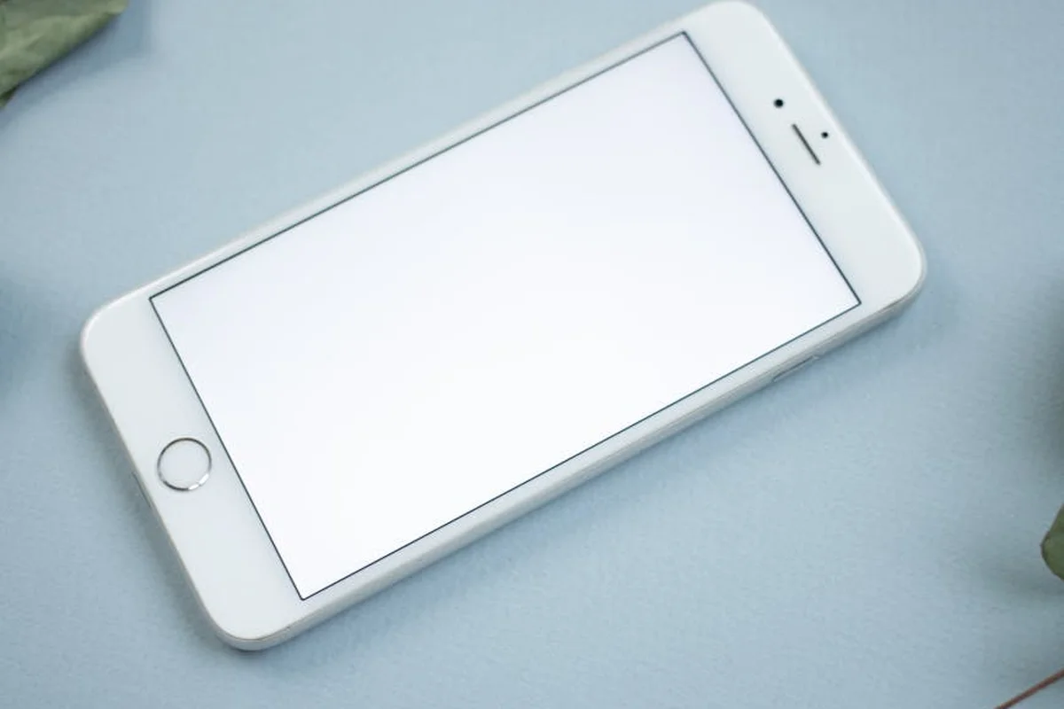 White smartphone lying diagonally on a pale blue surface.