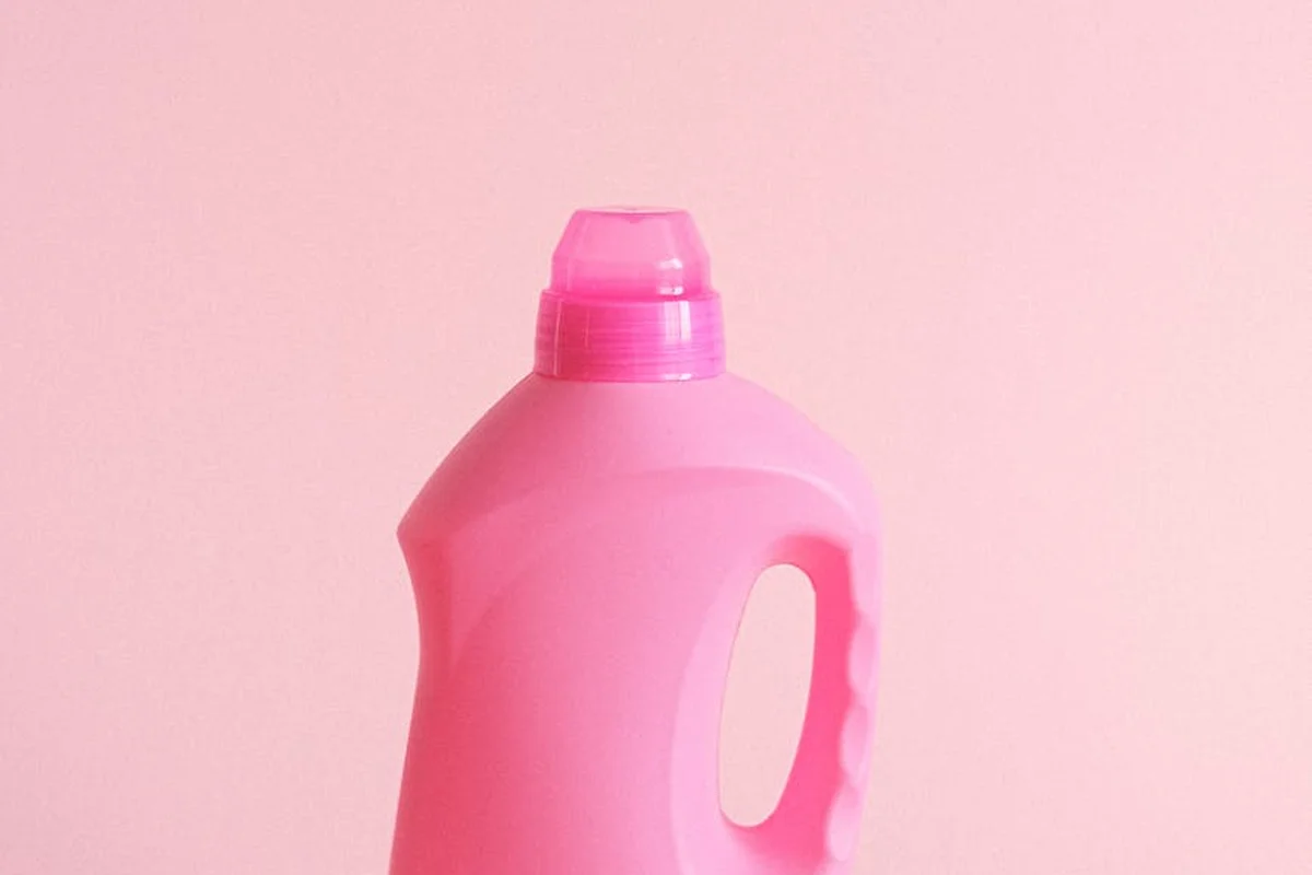 Plastic pink laundry detergent bottle against a pink background