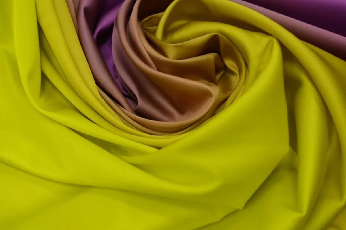 Close-up of bright yellow and purple polyester fabric folded into soft, silky folds.
