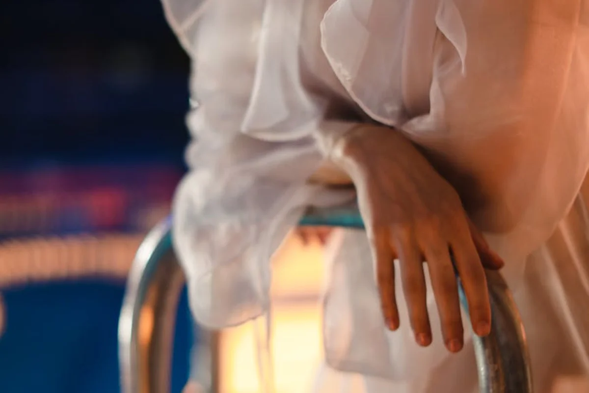 Close-up of a translucent white sheer fabric cascading over a metal pool railing with a blurred pool background