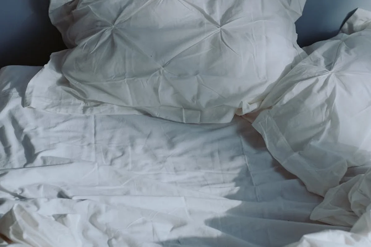 White linen bedding and pillows laid out on a bed, displaying soft, breathable fabric.