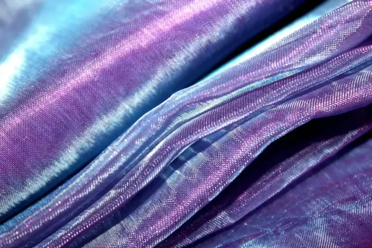 Close-up of iridescent purple and blue satin fabric with soft folded texture