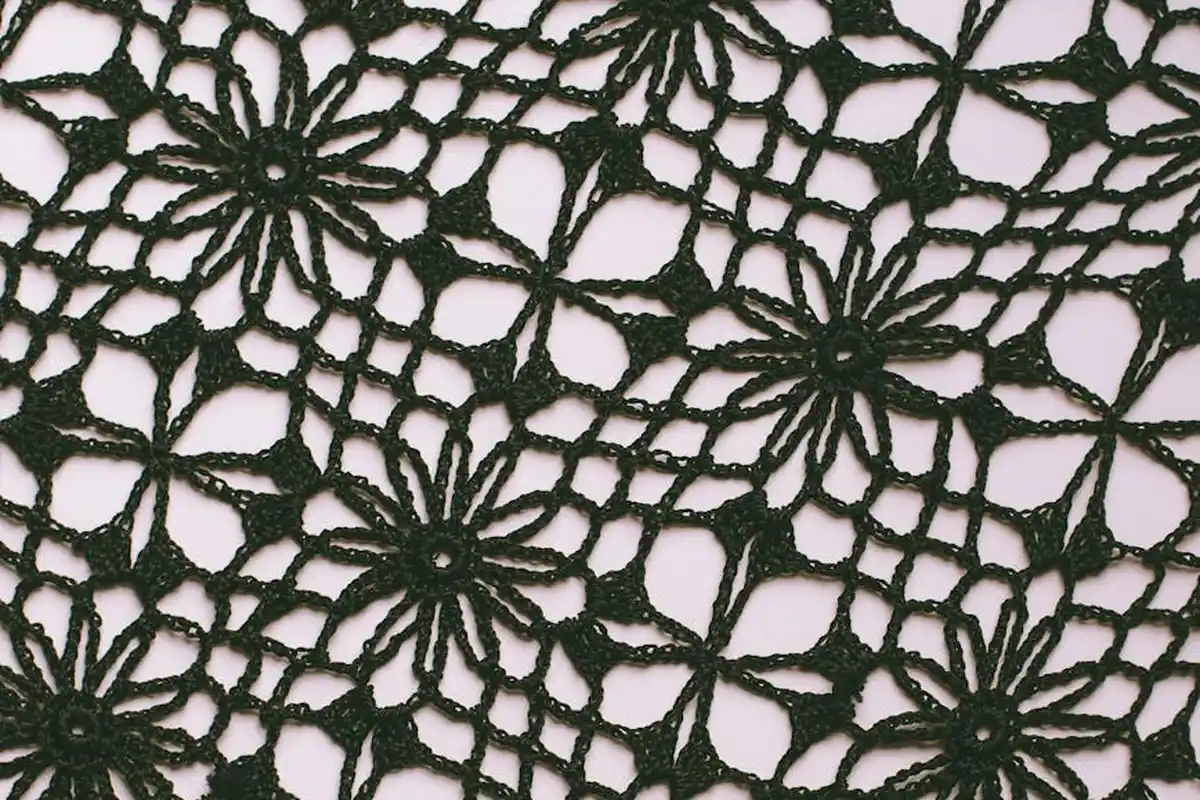 Close-up of black floral lace fabric with intricate stitches and a delicate texture.