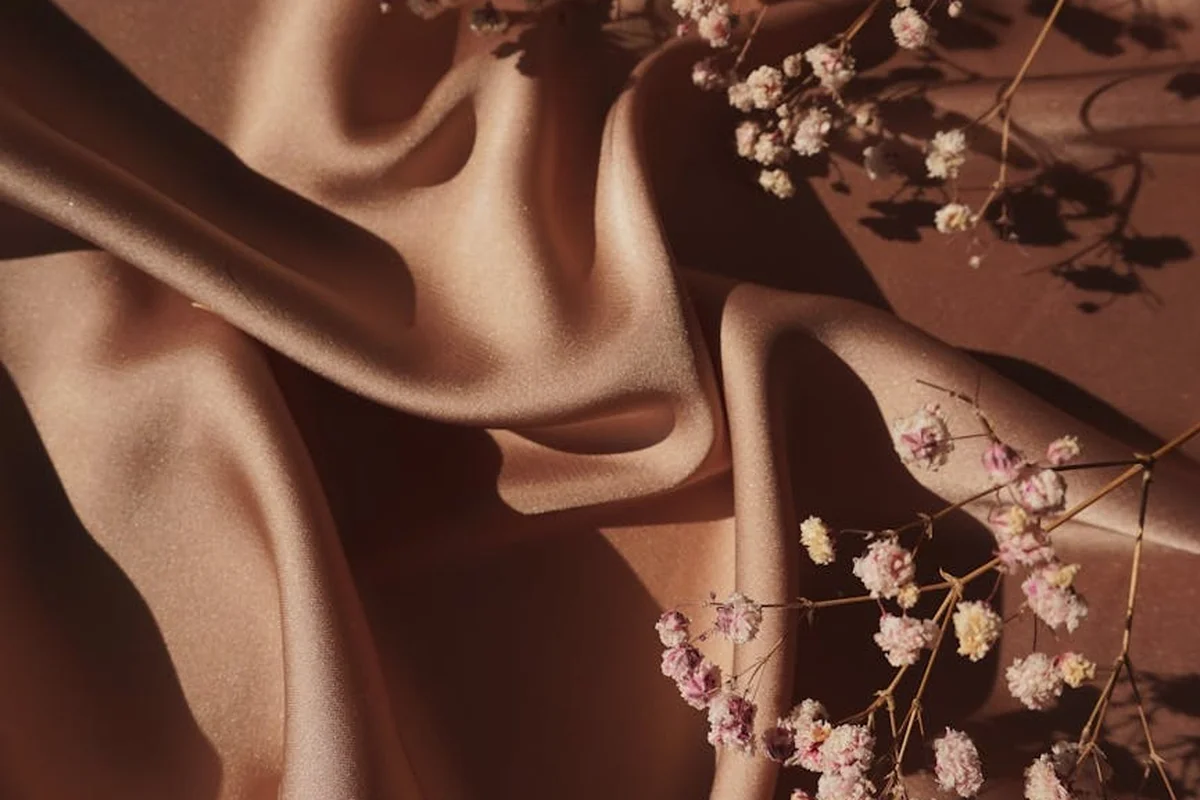 Brown satin fabric with delicate white and pink flowers, illustrating the fashion context of rayon's environmental considerations