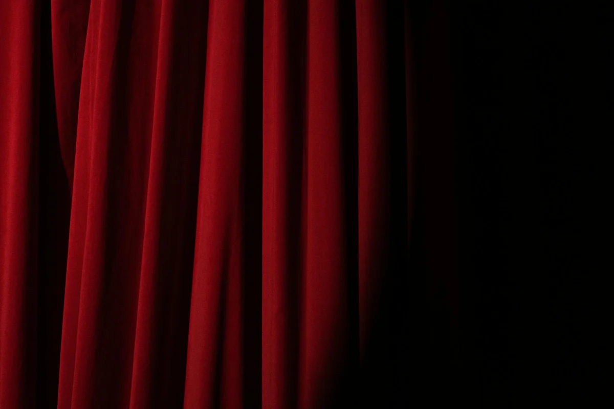 Red velvet curtain panels hanging against a dark backdrop