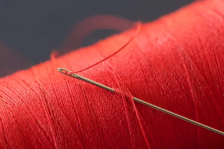 Close-up of red thread with a sewing needle for mending stretch fabrics