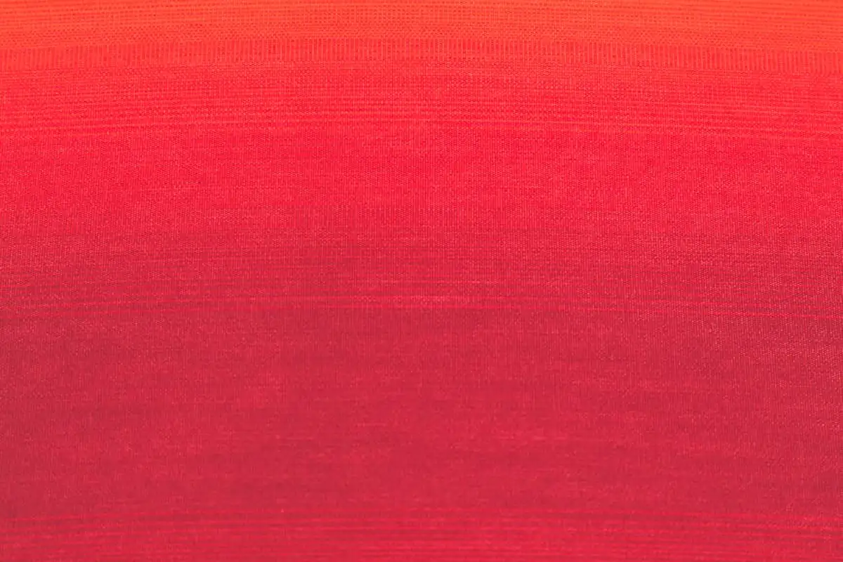Close-up of red fabric with a subtle gradient and visible weave, representing solution-dyed acrylic fibers designed for UV fade resistance.