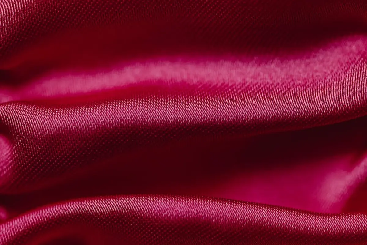 Close-up of rich red satin fabric with soft folds and a glossy sheen