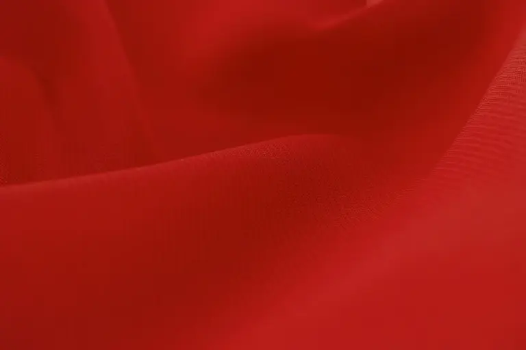 Close-up of red suede-like fabric showing soft nap and folds.