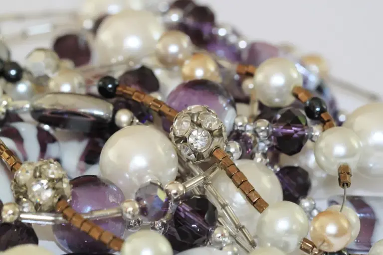 Close-up of assorted rhinestones, crystals, pearls, and beads scattered together, illustrating embellishment materials