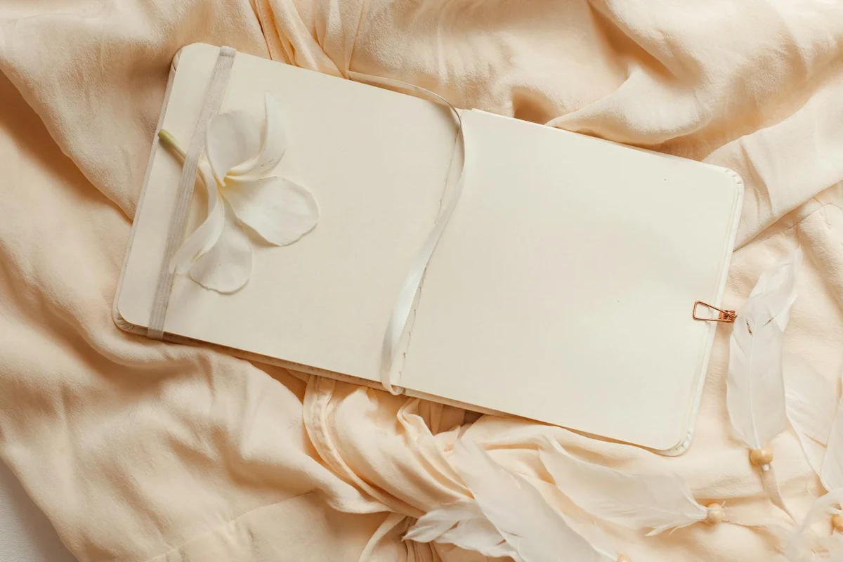 Cream silk fabric with a blank notebook and ribbons, suggesting gentle handling and careful care of silk fabrics.