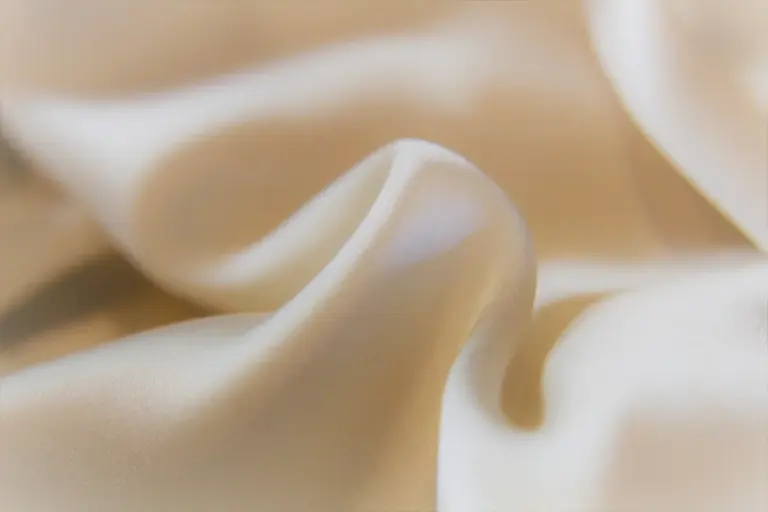 Close-up of ivory silk fabric with soft folds and smooth texture