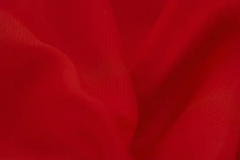 Close-up of red silk fabric showing smooth texture and gentle folds