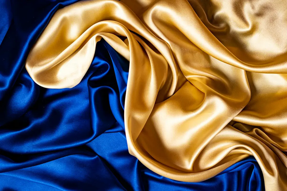 Close-up of blue and gold silk fabrics with smooth, lustrous folds and rich sheen.