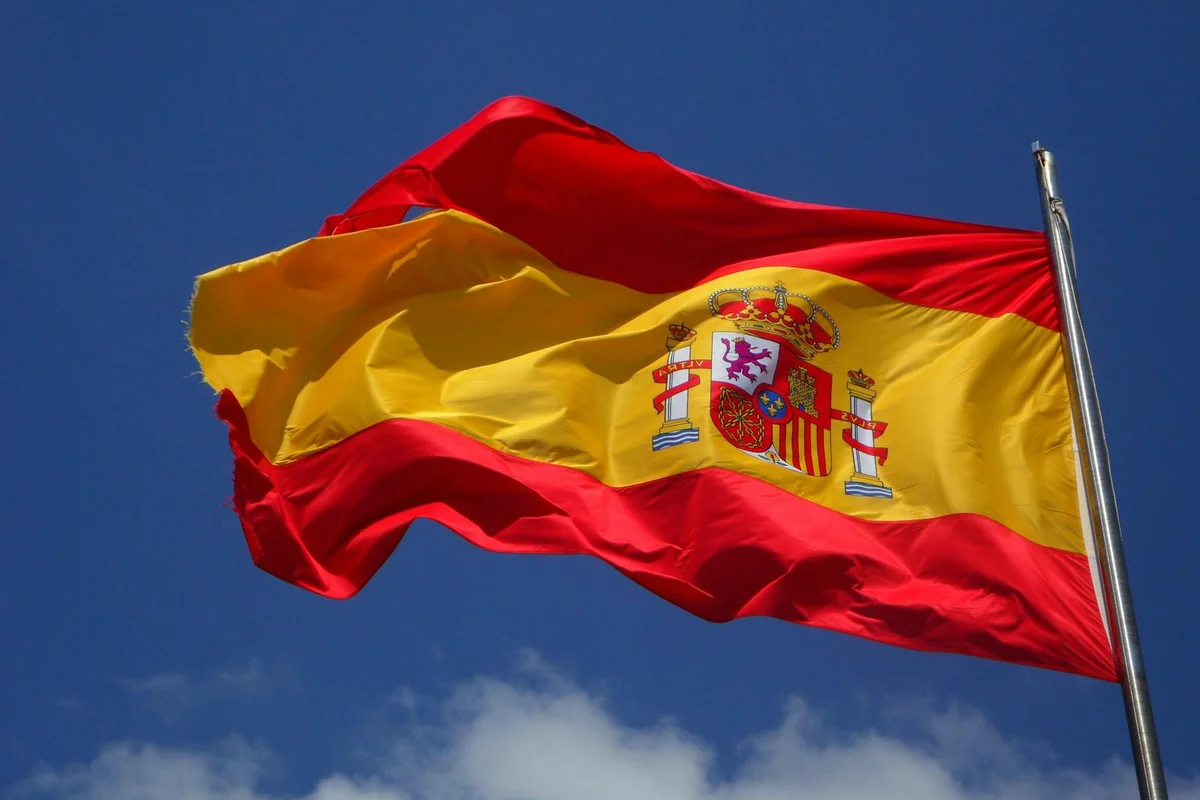 Spanish flag waving in the wind against a blue sky.