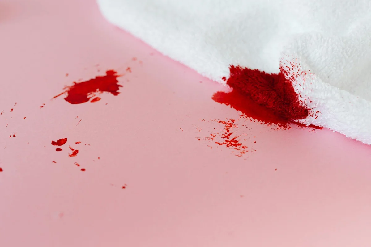 Close-up of red stains on light pink fabric, illustrating stain types to address in a kit