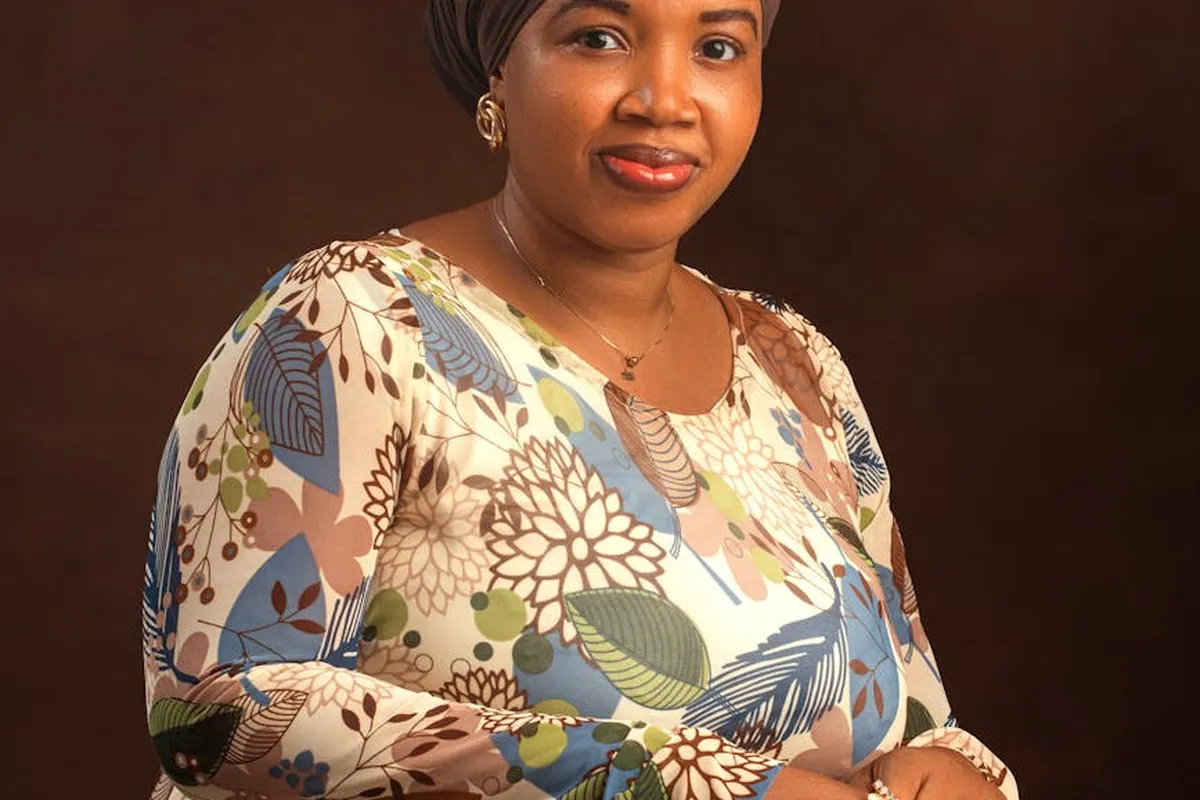 Portrait of a woman wearing a colorful floral top made of stretch fabric against a dark studio background.